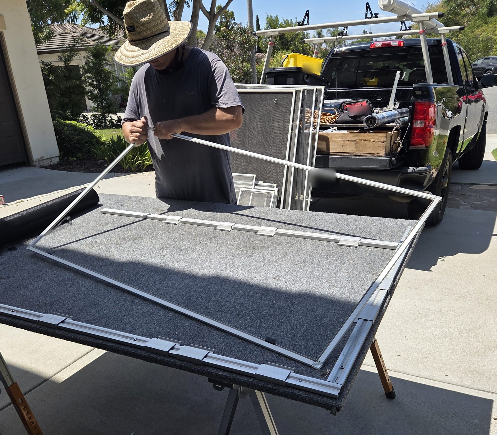Zac assembling a white window screen frame at a mobile worktable