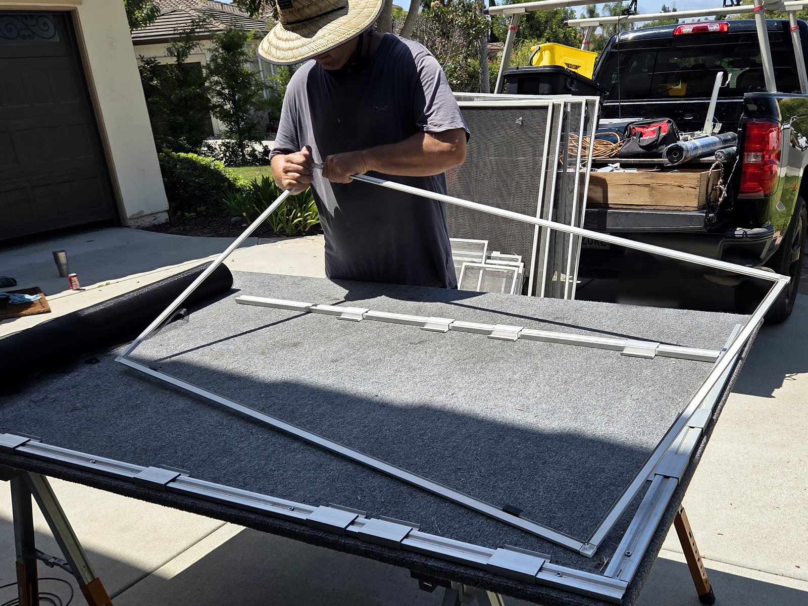 Zac joining white aluminum window screen frame pieces at a mobile worktable