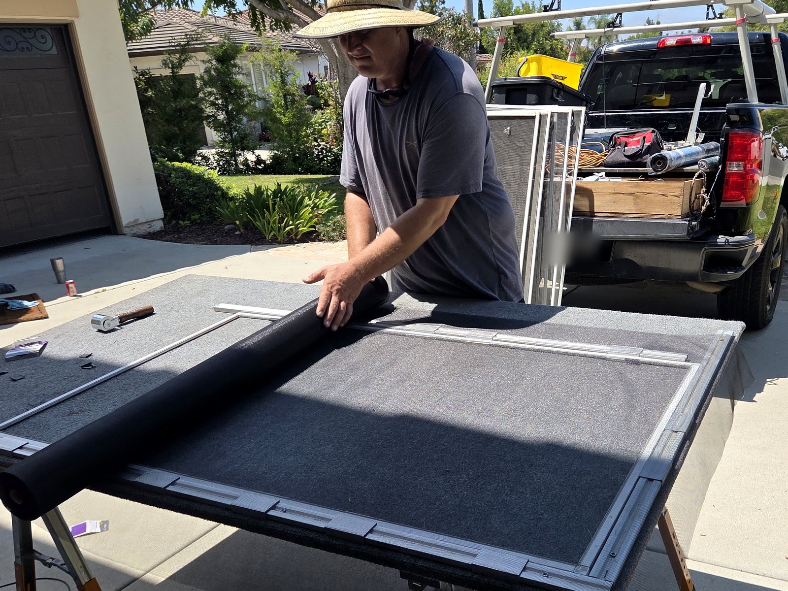 Zac unrolling standard charcoal screen mesh over a window screen frame